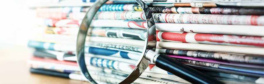 Stack of newspapers and magnifying glass
